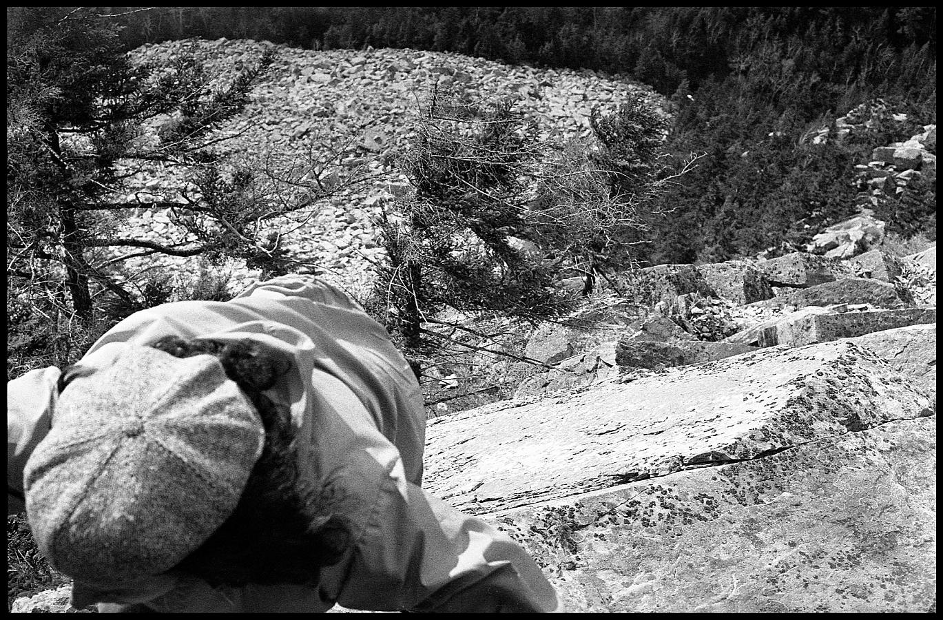 24a.jpg - After we'd rested, we looked up at the 600 foot cliff behind us and seeing numerous cracks and ledges, we looked at each other and said, "We can climb that."  But when we got part of the way up and started seeing pitons sticking out of the rocks it occurred to us that maybe free climbing was not such a great idea after all.  But still, it looked like it was easier to go up than down, so on we went.